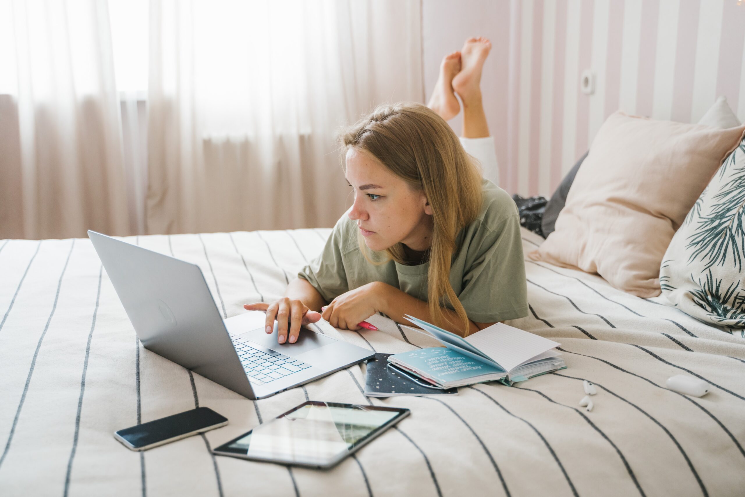 A lady working on a laptop on her bed