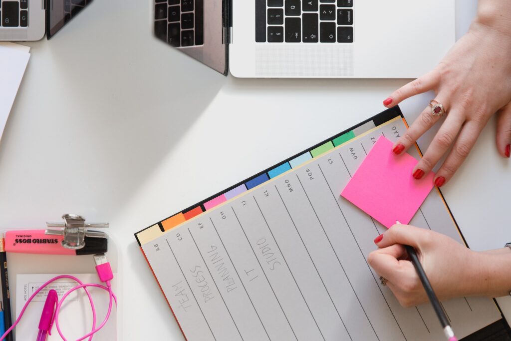 Lady writing on a Post-It note that's on top of a planner