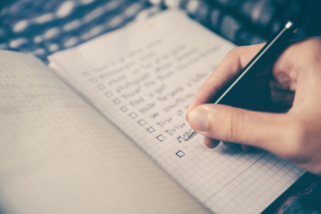 A person writing a list of goals with boxes next to each one ready to be checked off when the tasks are done