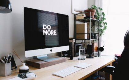 A computer on a desk with DO MORE. displayed on the screen