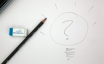 An eraser and pencil on a piece of paper with a drawing of a question mark inside a circle